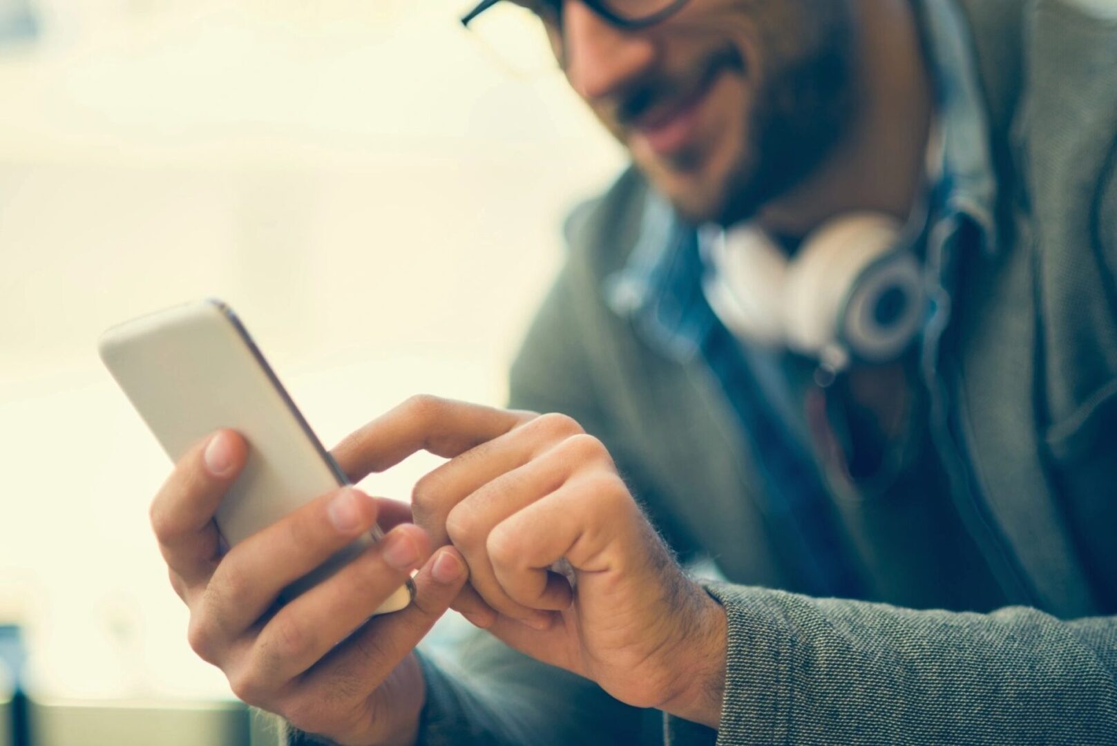 A man wearing headphones looking at his phone.