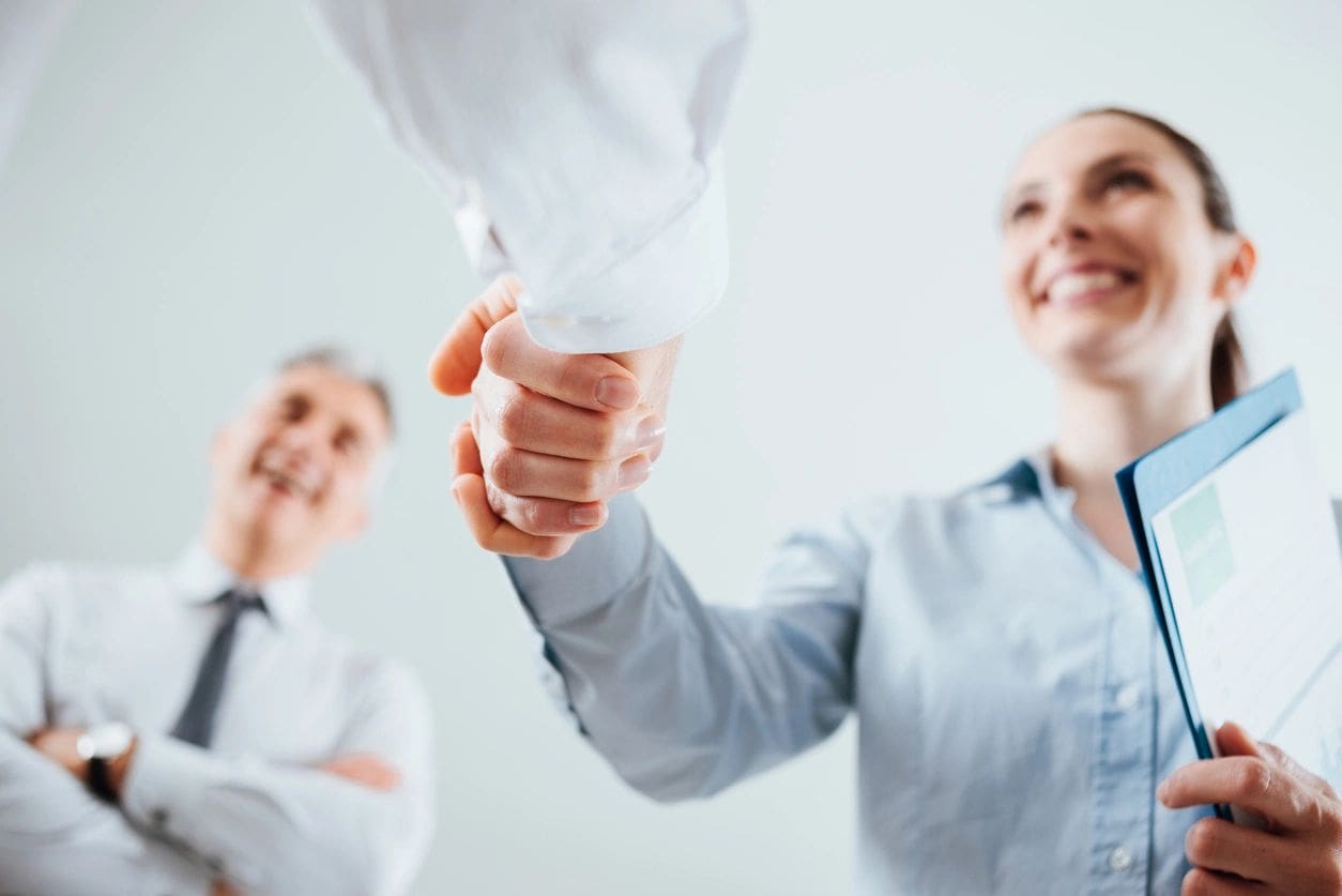 Two people shaking hands in a room.