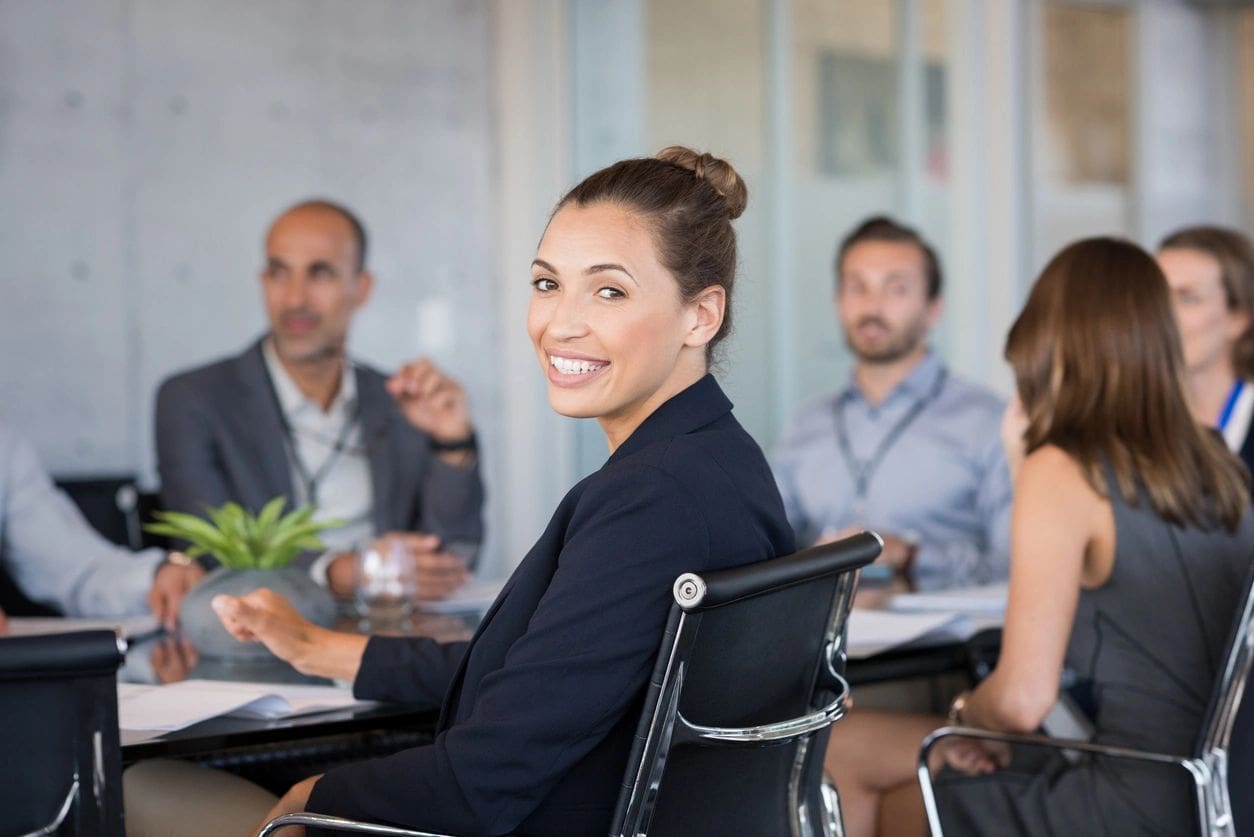 A woman sitting in front of other people at a table.